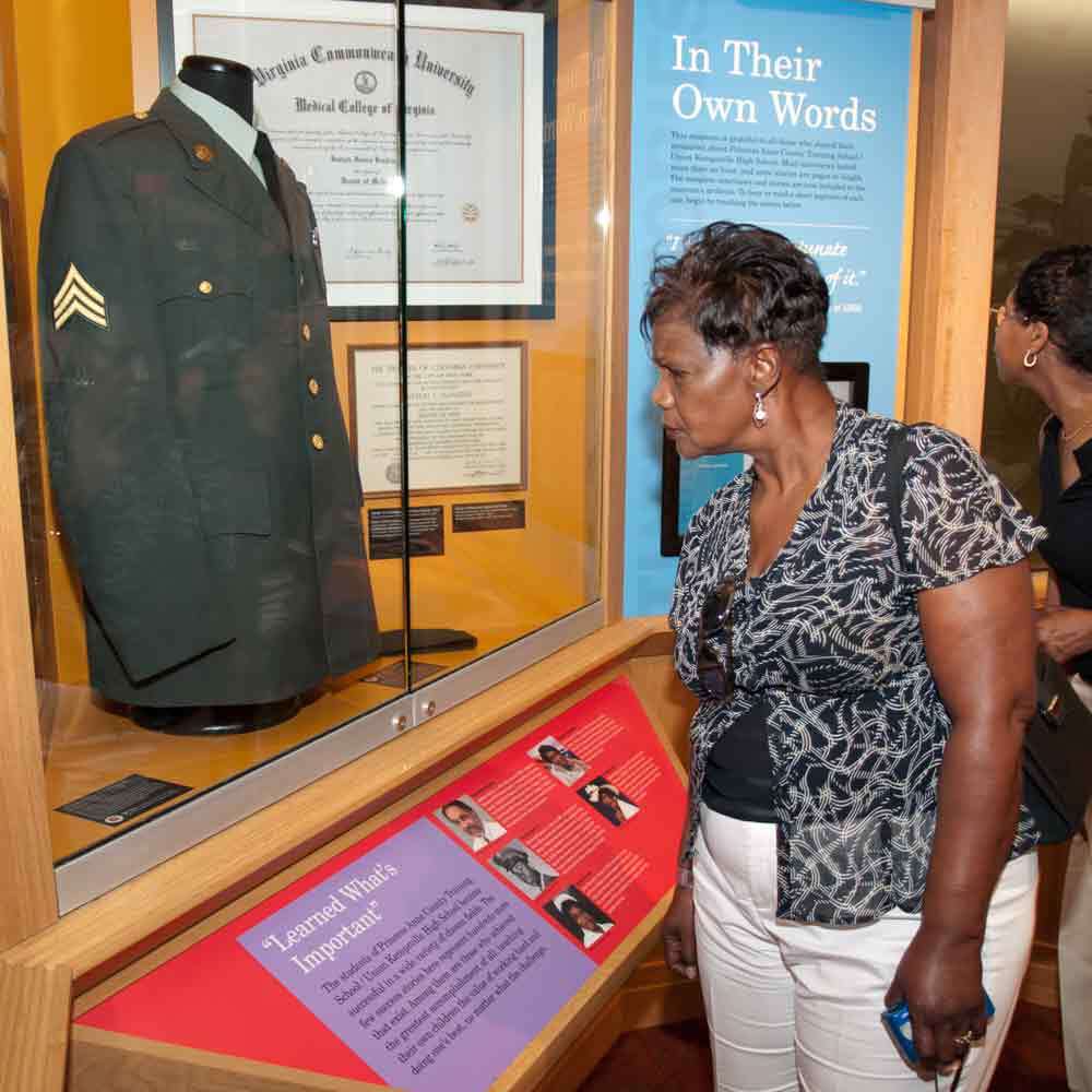 Visitors Looking at Display Case of Military Uniform